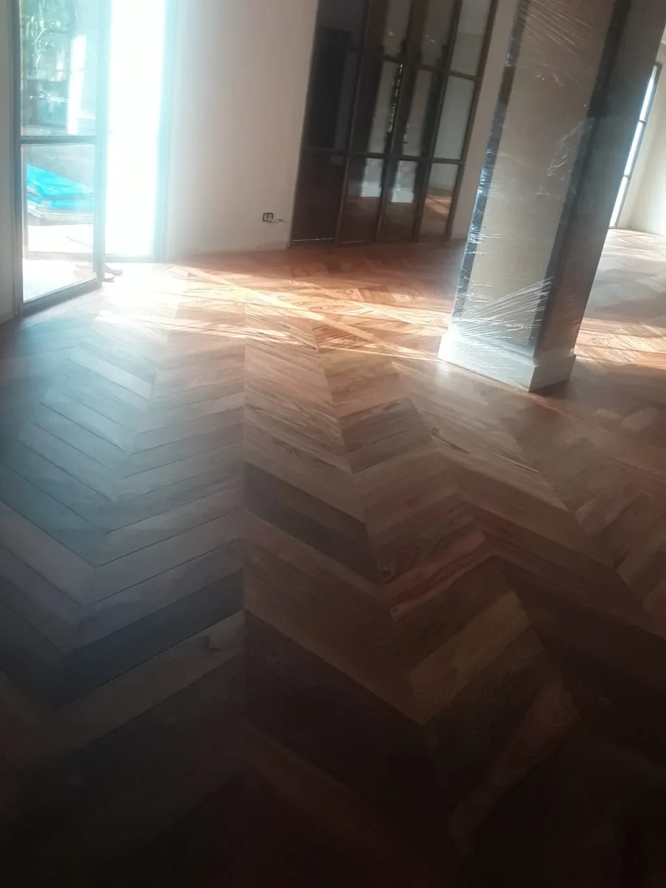 Parquet en bâton rompu dans une grande pièce éclairée par plusieurs baies