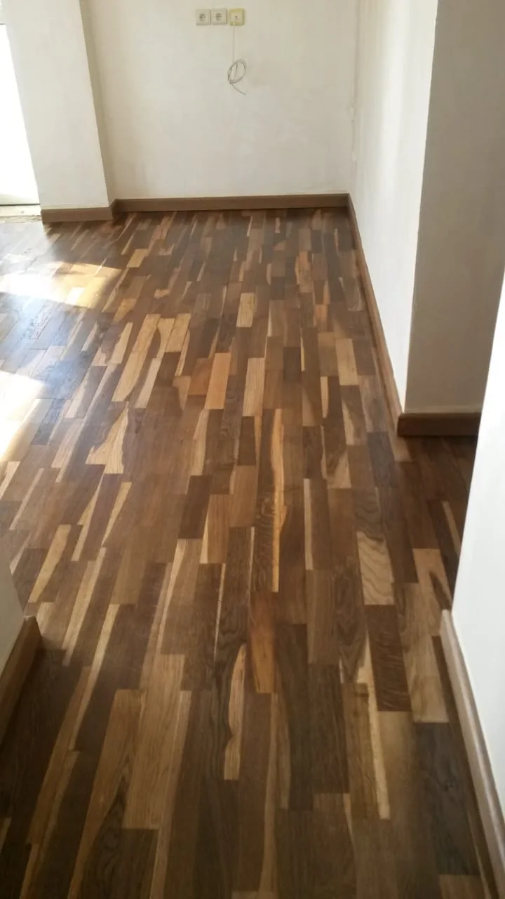 Parquet aux lames brunes contrastées dans un couloir lumineux