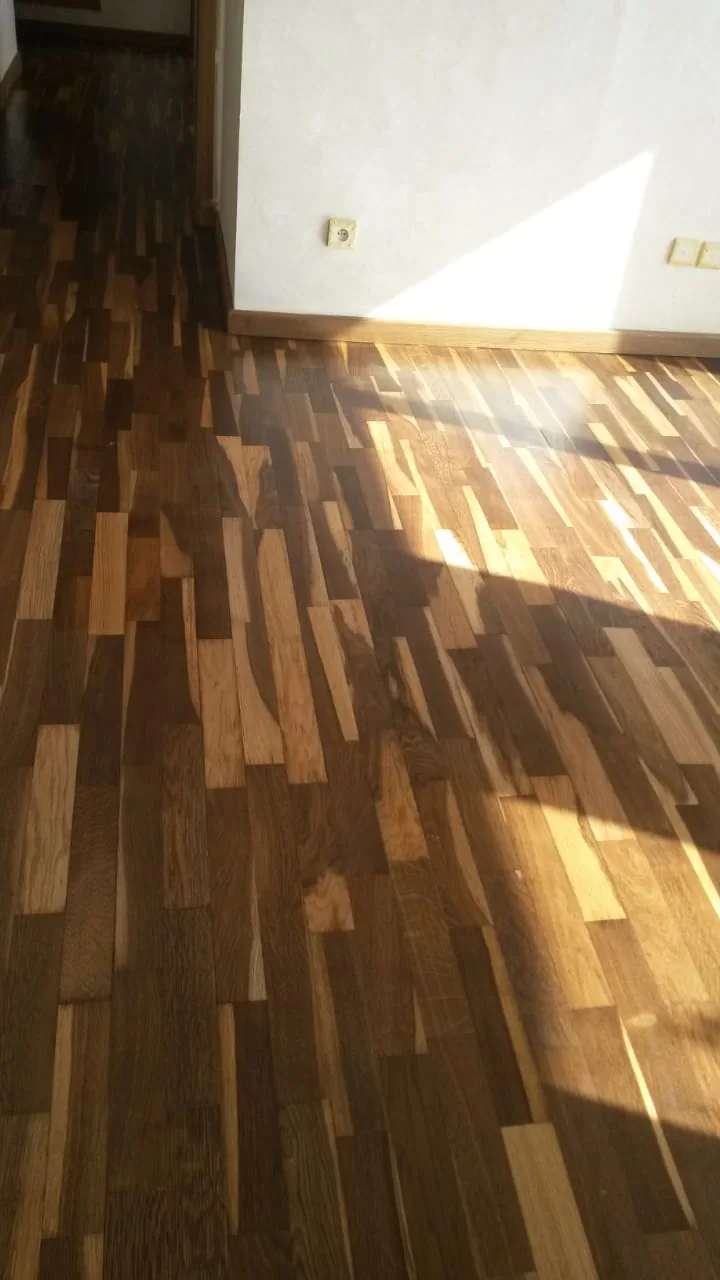 Lames de parquet brun éclairées par une bande de lumière naturelle