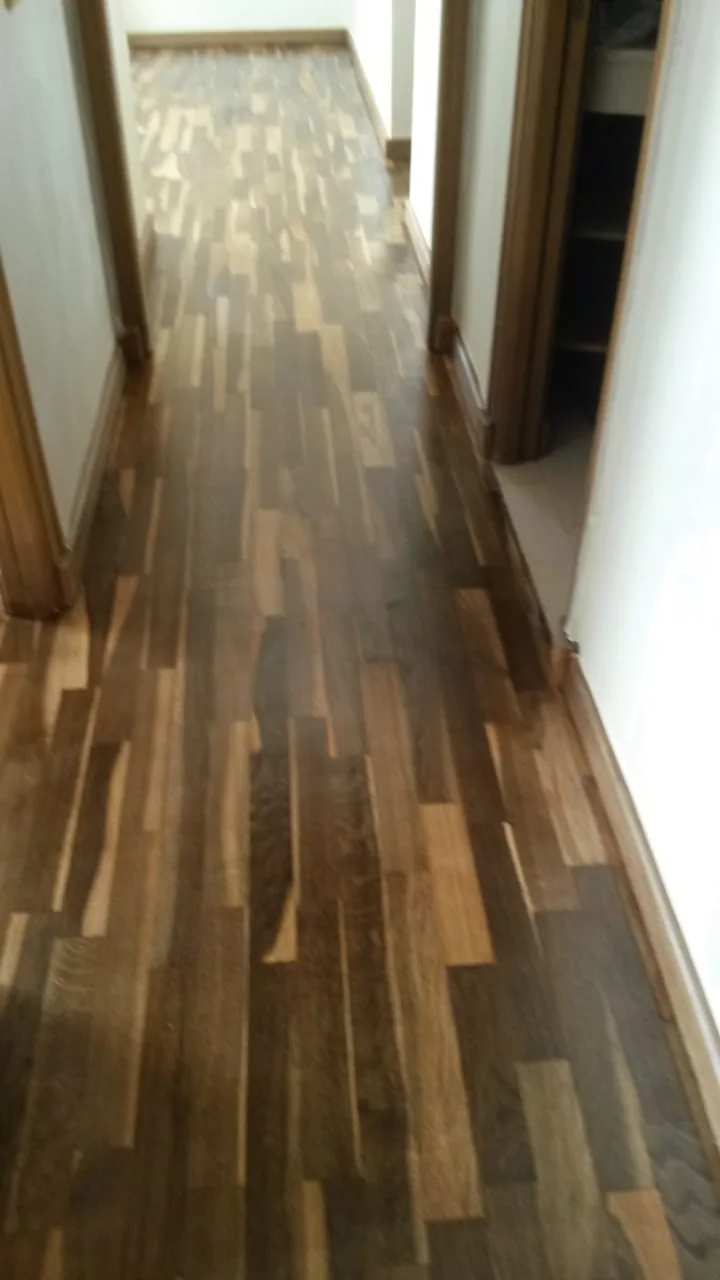 Passage étroit couvert de lames de parquet aux nuances claires et foncées