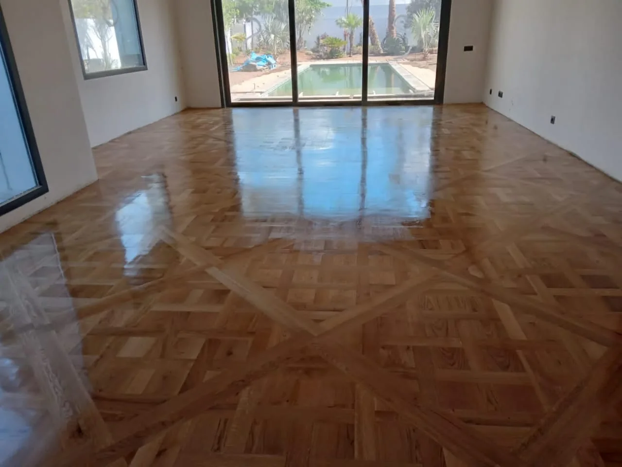 Parquet mosaïque aux reflets brillants dans une pièce avec fenêtre