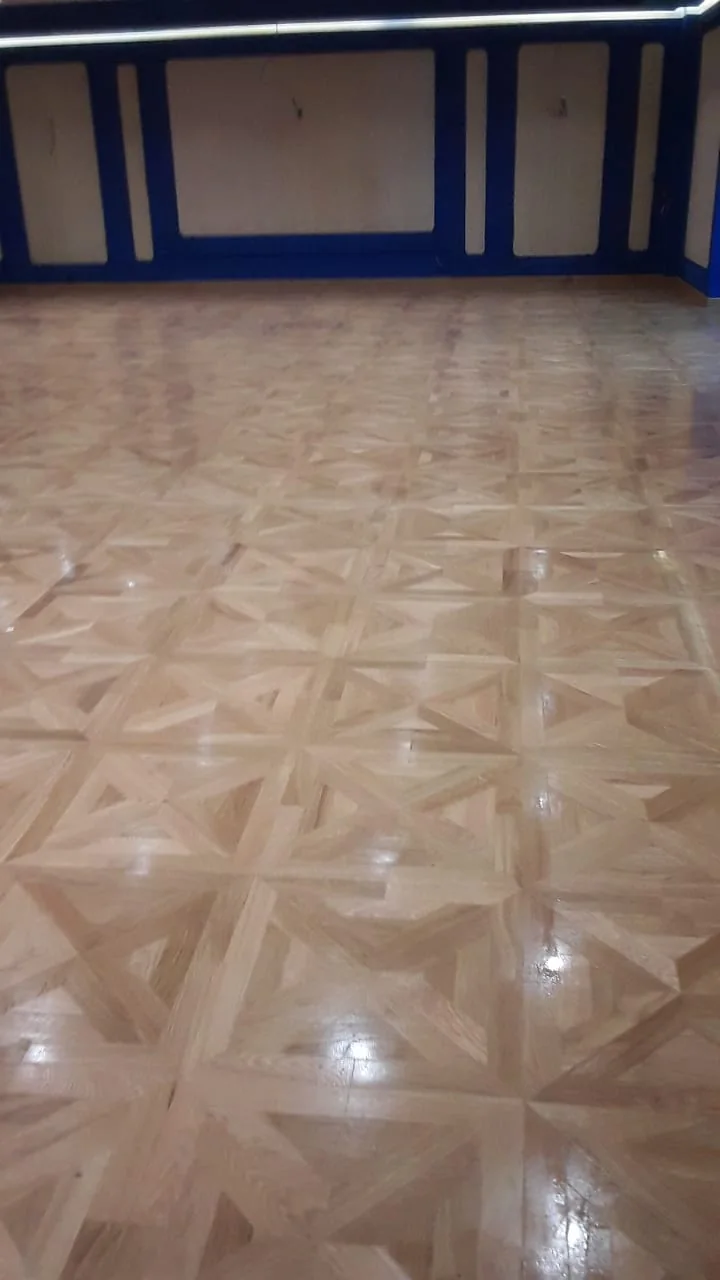 Parquet mosaïque brillant dans une salle avec encadrements foncés