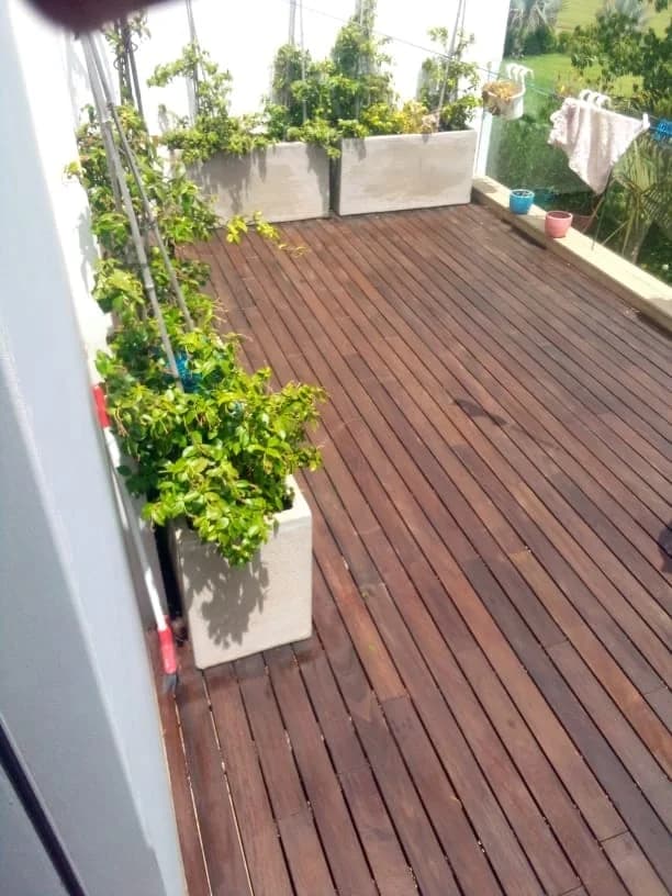 Balcon en lames de bois entouré de jardinières et de plantes